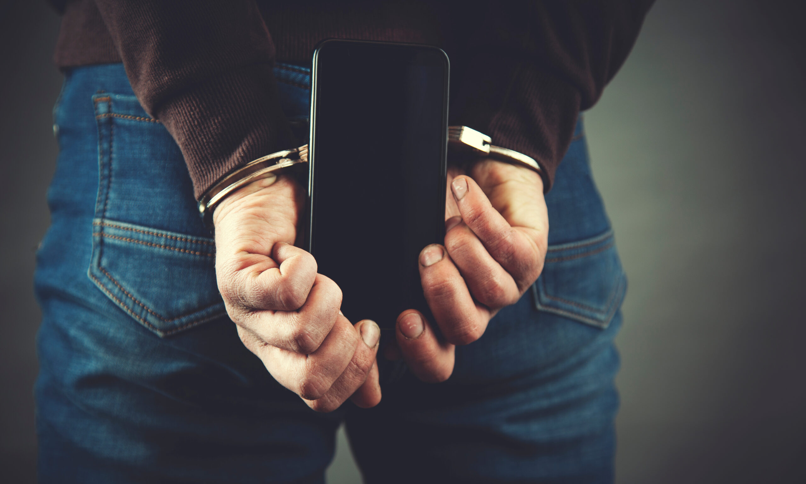 young business man hand handcuffs and phone
