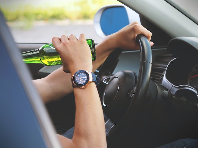 person drinking a beer while driving