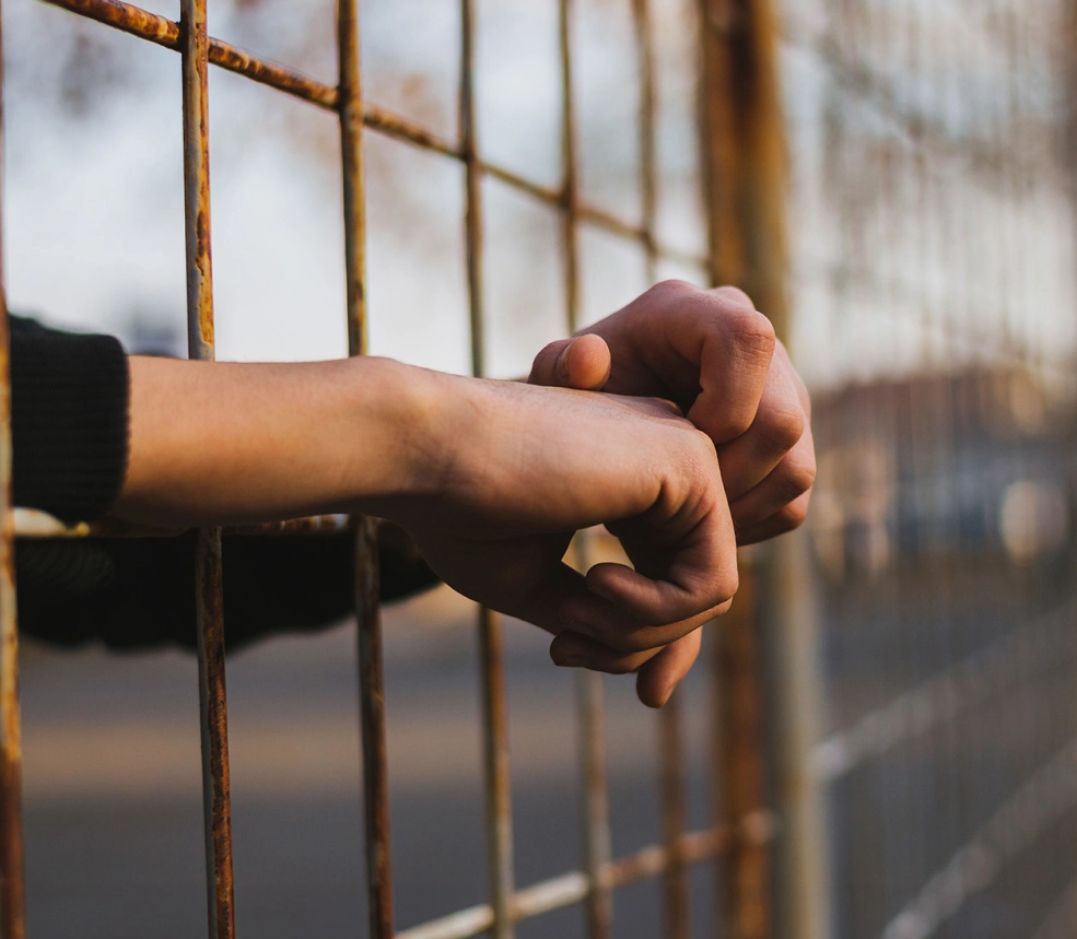 hands sticking through jail fence