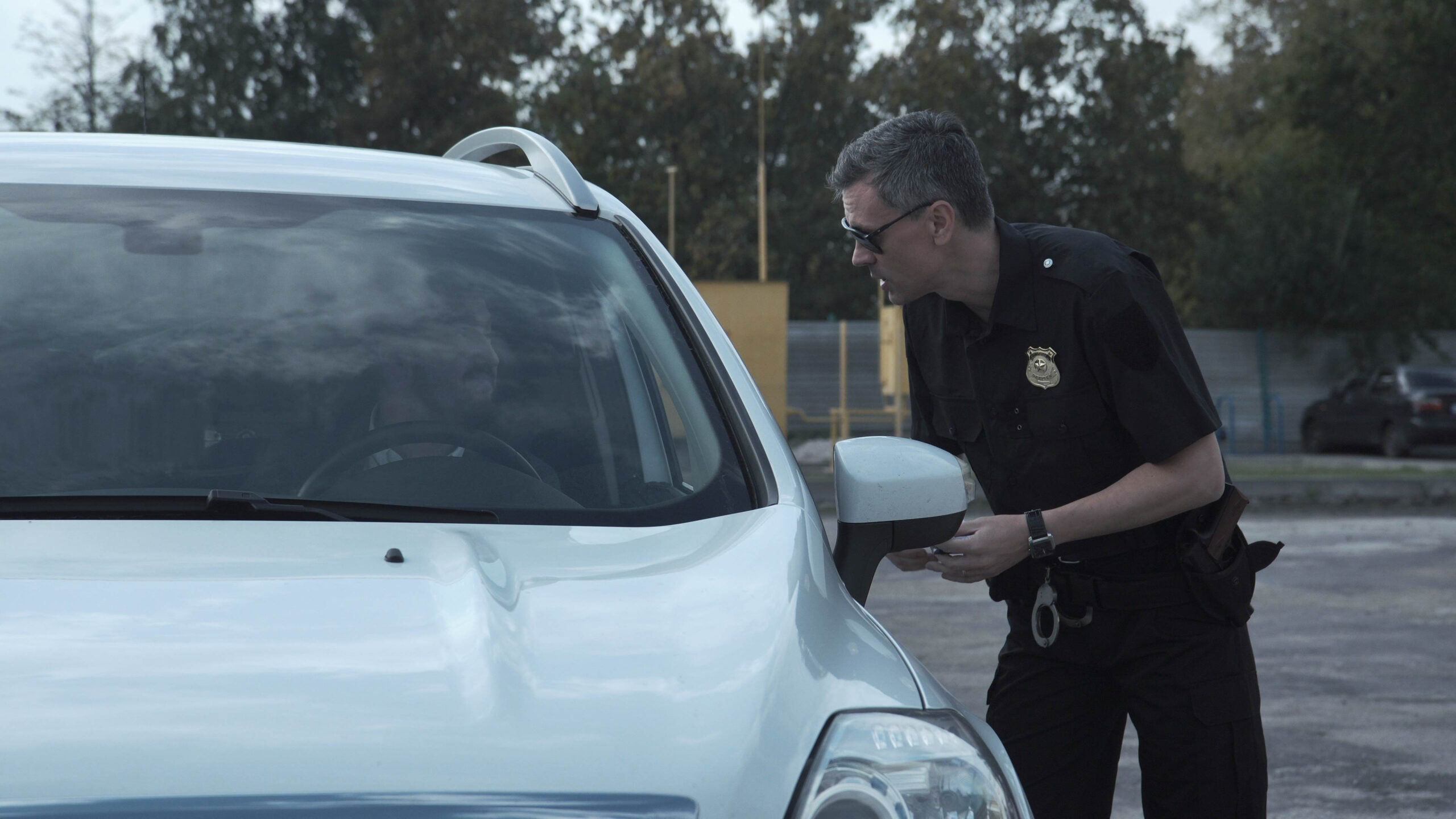 Police officer stopping the driver of a vehicle and questioning him over an alleged offense through the open window of the car