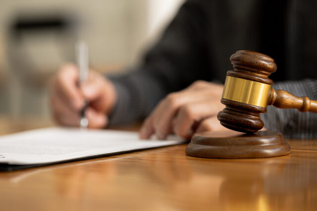 The judge's hammer is placed on the table, the lawyer concept assumes that the defendant defends the client in order to win the case or gain the greatest benefit in accordance with the law.